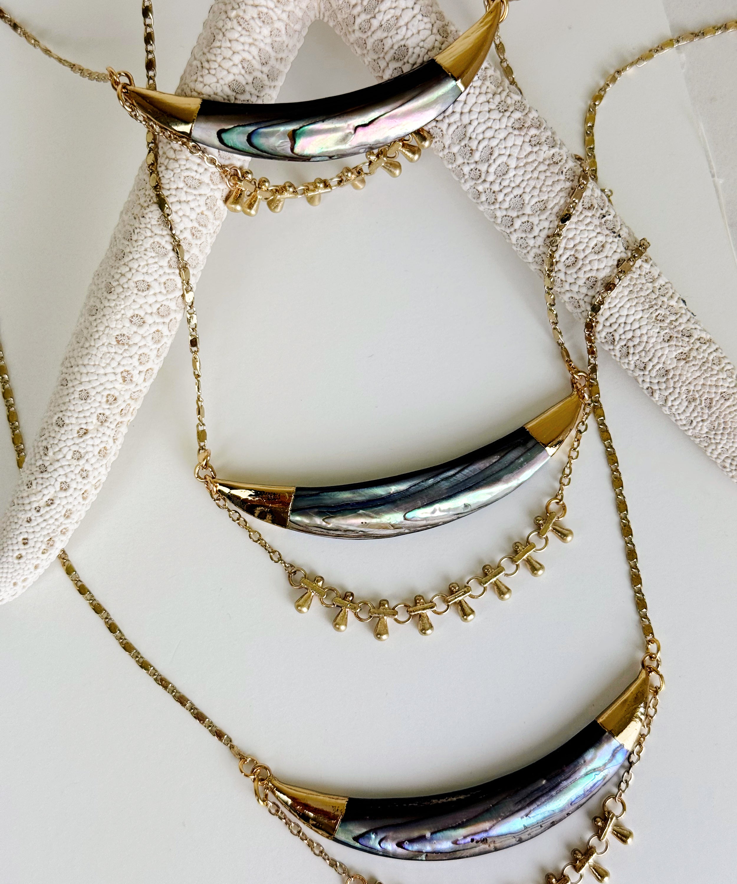 Three Darya abalone pendant necklaces laying against a large starfish. Handcrafted by Alysian.