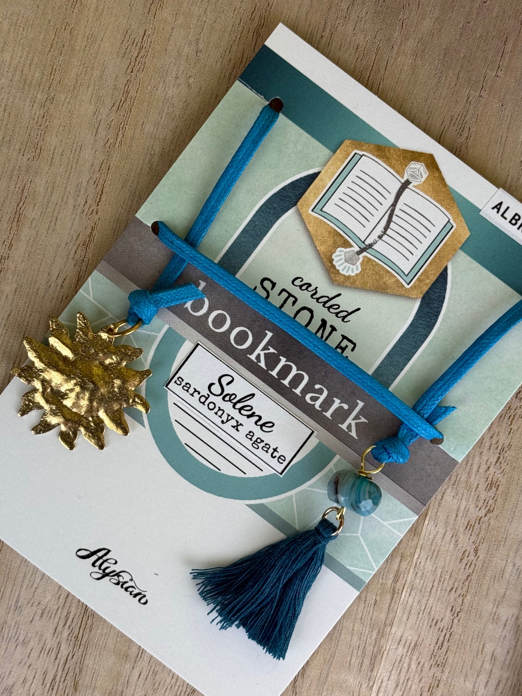 Decorative Solene agate corded bookmark with a tassel on a branded card.