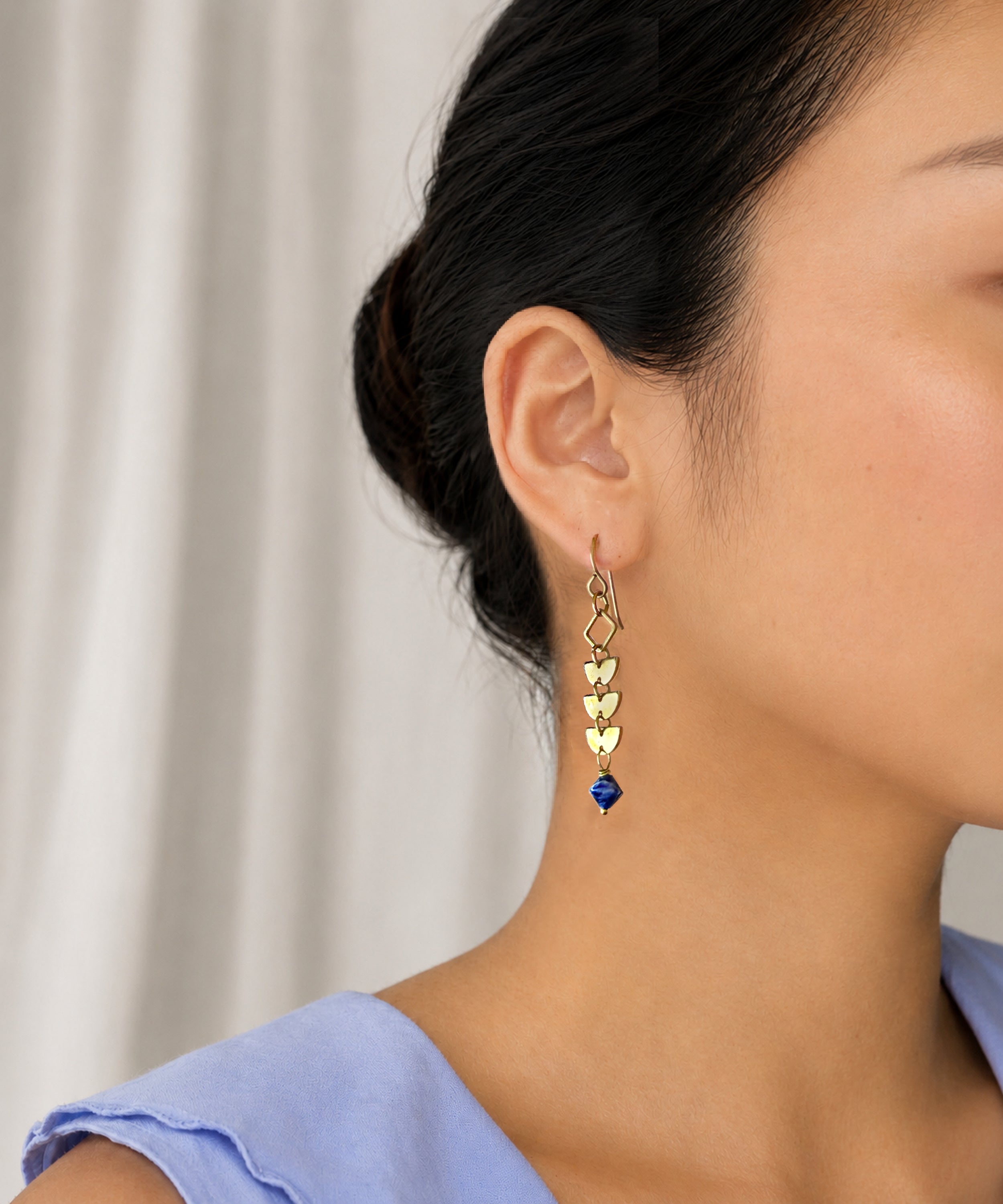 Close-up of a woman with hair back wearing the brass linear Alune Sodalite Earring. Handcrafted by Alysian.