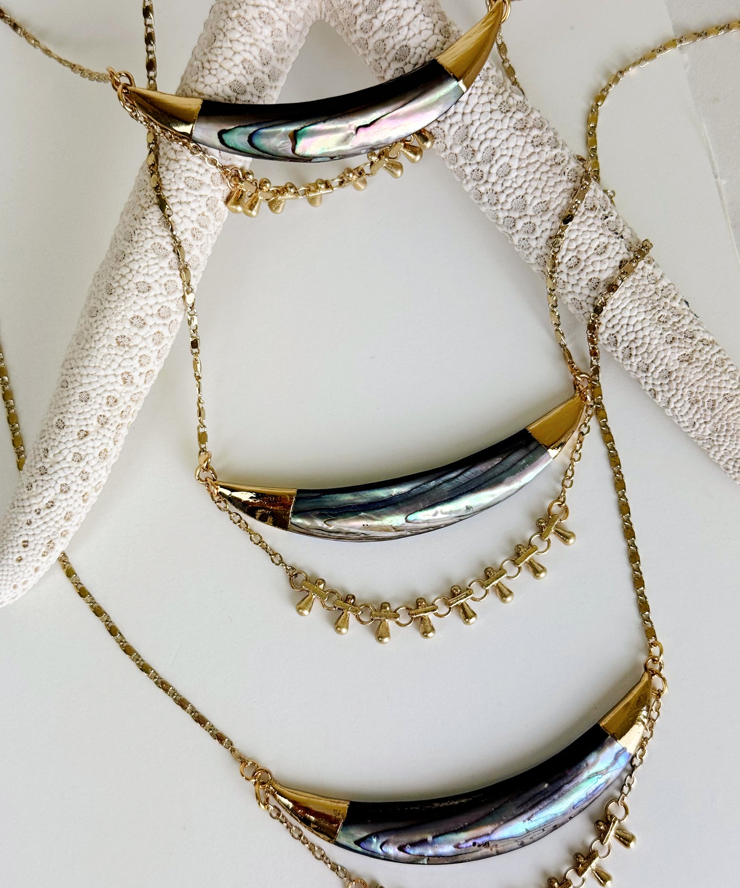 Three Darya abalone pendant necklaces laying against a large starfish. Handcrafted by Alysian.