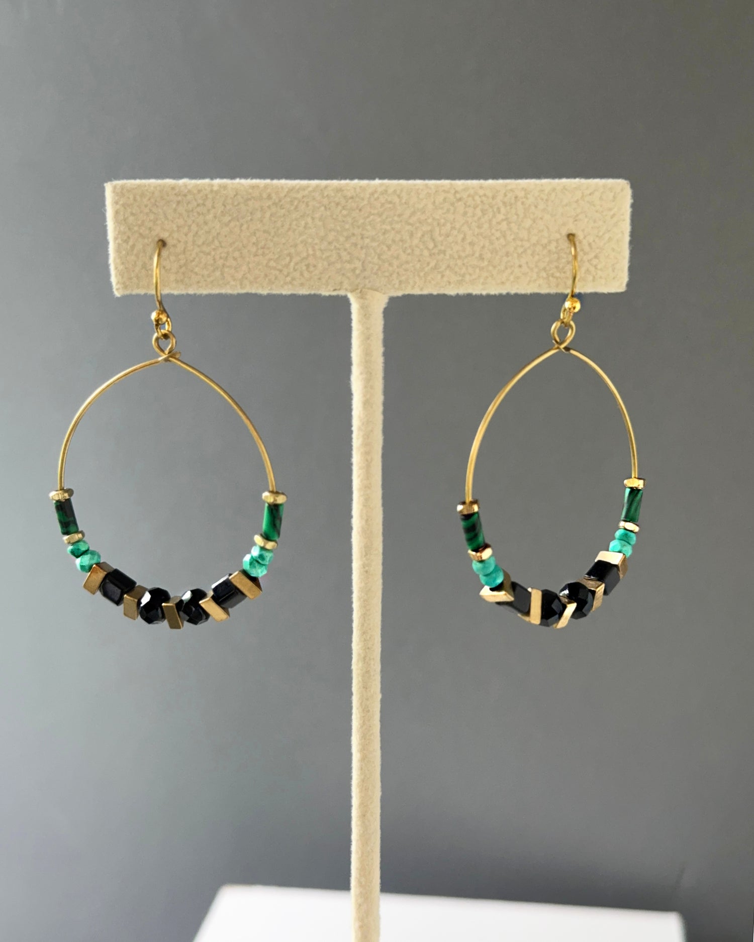 Brass hoop earrings with green malachite, turquoise stones, black beads and edgy brass acccents on an earring stand — Adira hoop by Alysian.