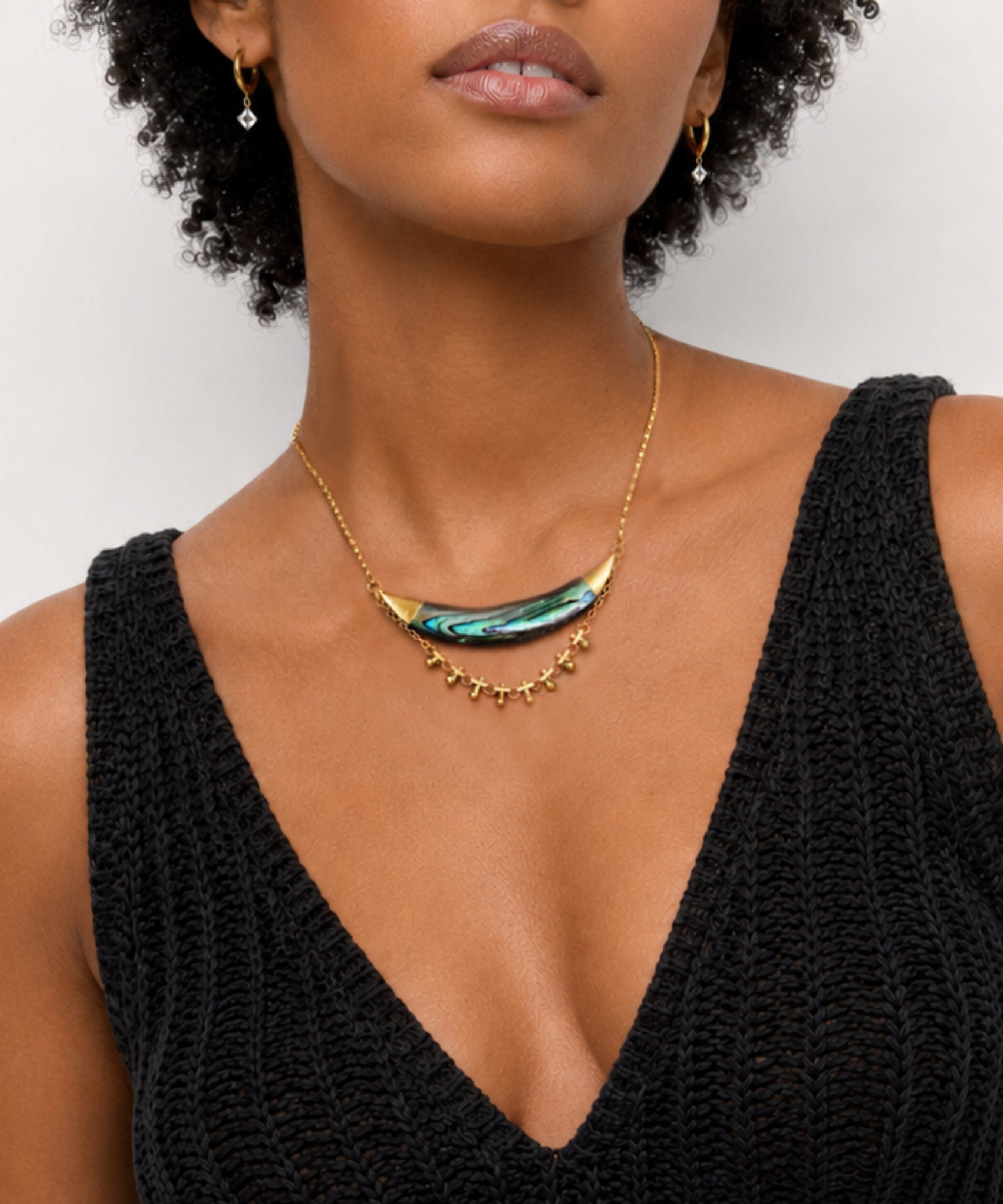Woman wearing the Darya Abalone Crescent  Necklace with a greens and blues and purple across the abalone, handcrafted by Alysian. 