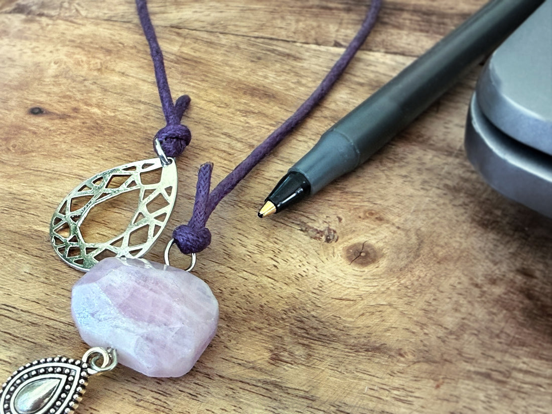Elira purple corded kunzite stone bookmark on a wooden surface next to a pen.