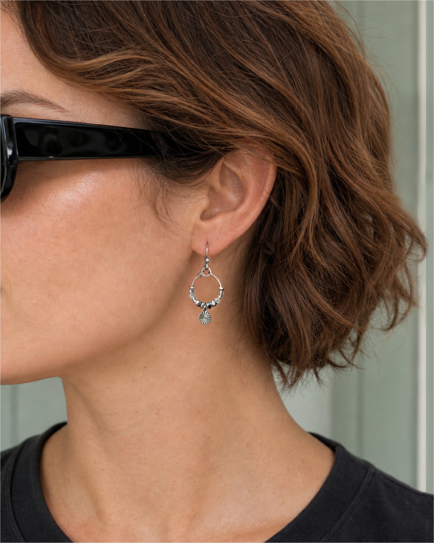 Handcrafted stainless steel wire hoop with labradorite stones and coin drop by Alysian modeled on an ear.