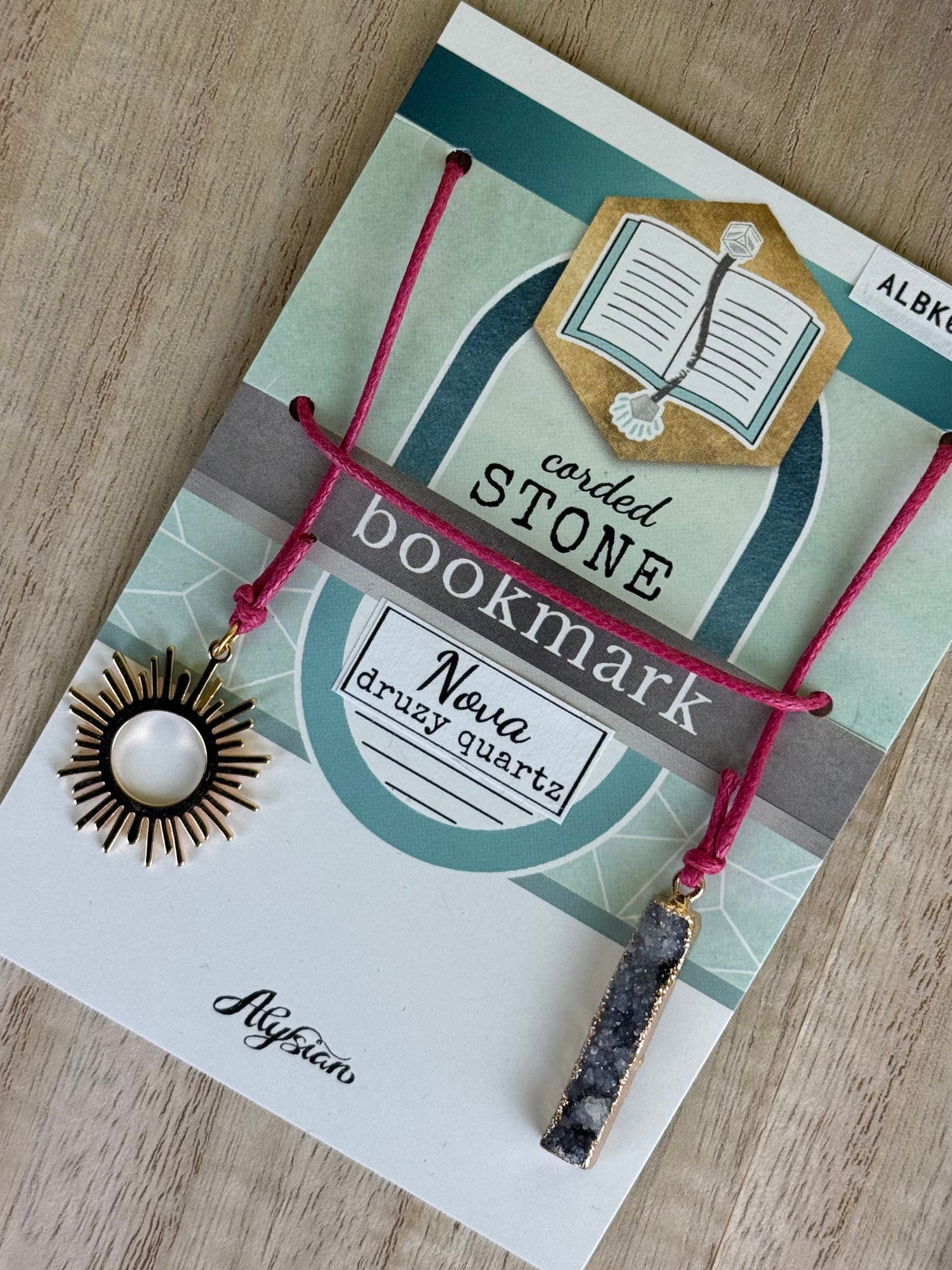 Nova druzy stone and gold sun bookmark with cord on a branded card.