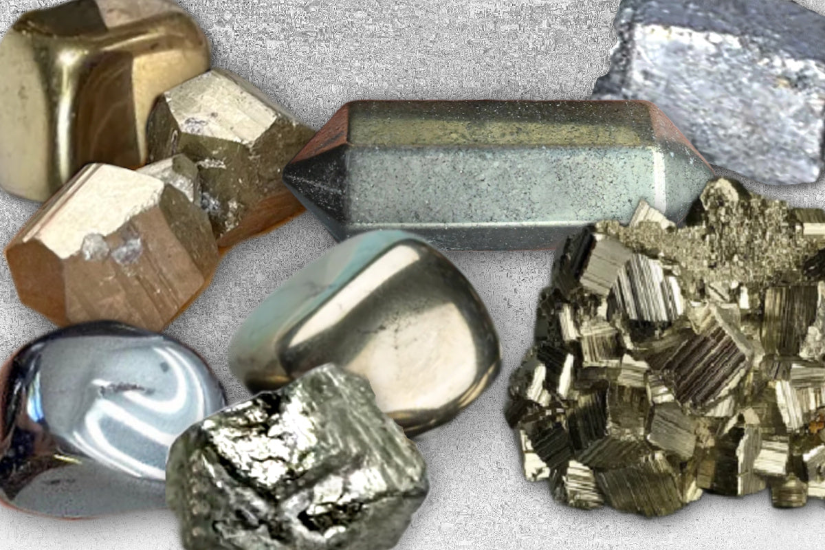 A grouping of sleek metallic pyrite and hematite stones in a range on golden and silver tones on a textured surface.