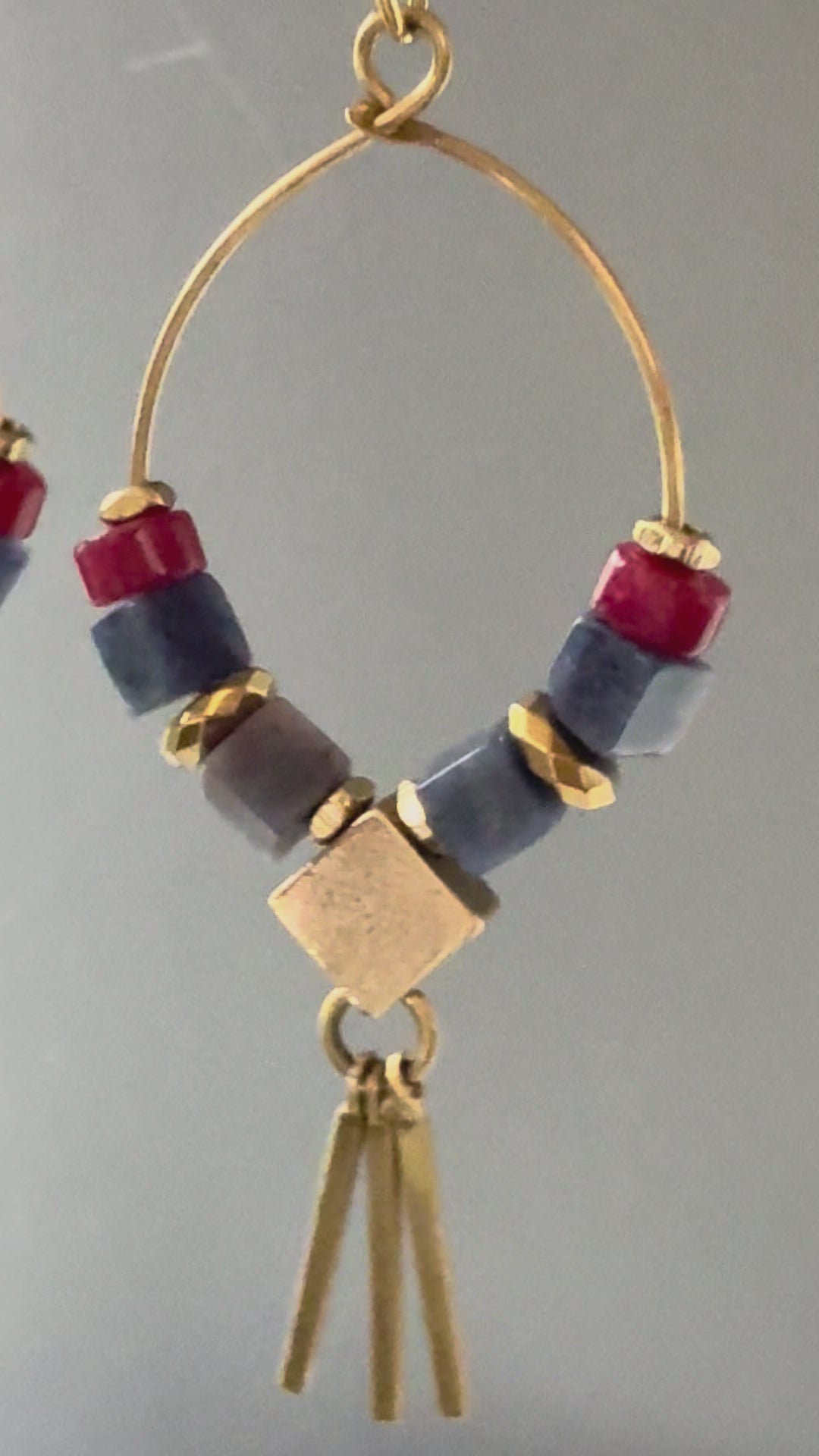 A video of Alysian Azra Sodalite Hoop Earrings close up, with smooth stones and shimmering faceted elements and brass metal fringe. 