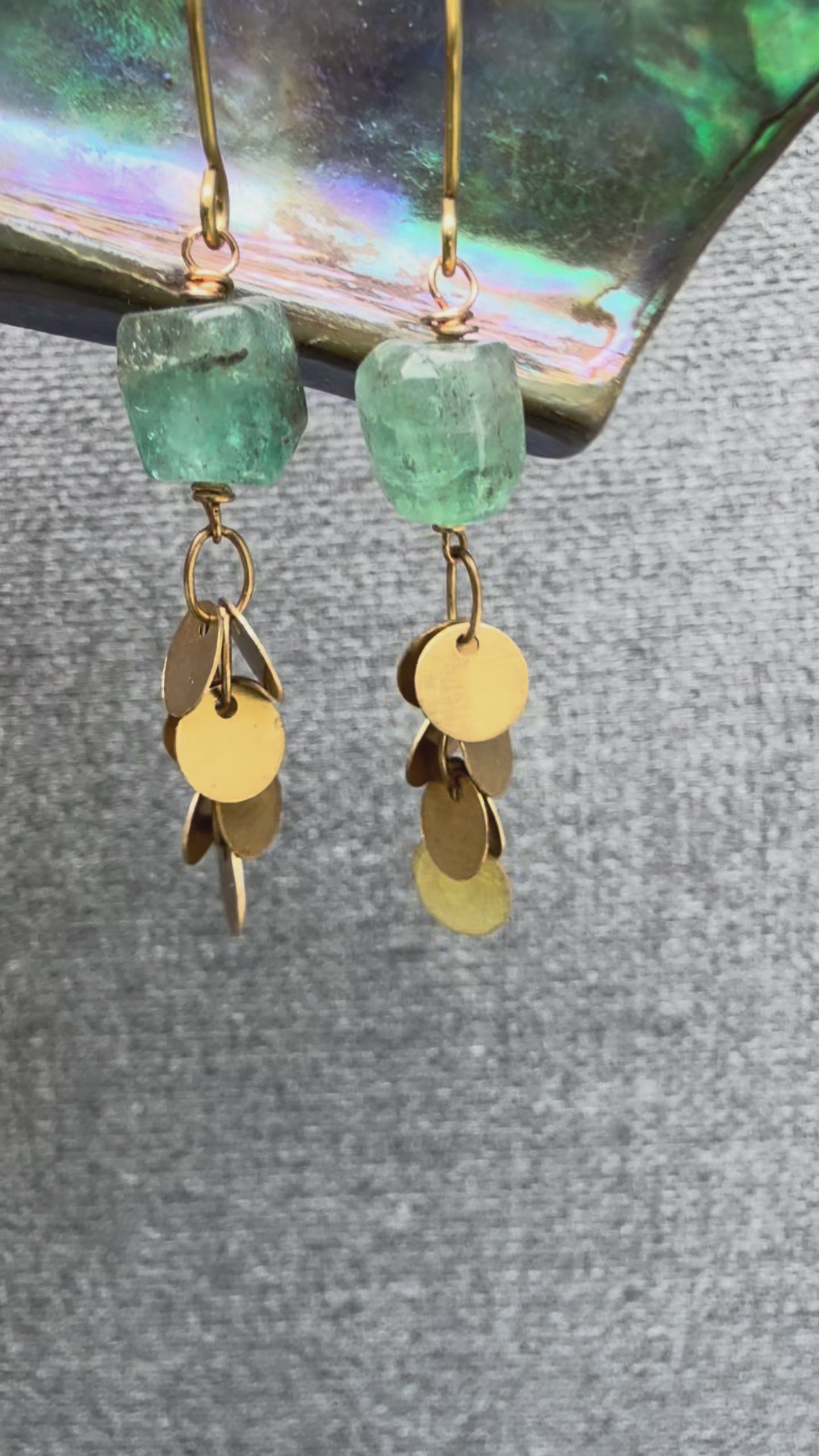 Video of pair of the Sedna Apatite Earring with organic-shaped smooth apatite stones and clusters of brass disc chain beneath, handcrafted by Alysian.